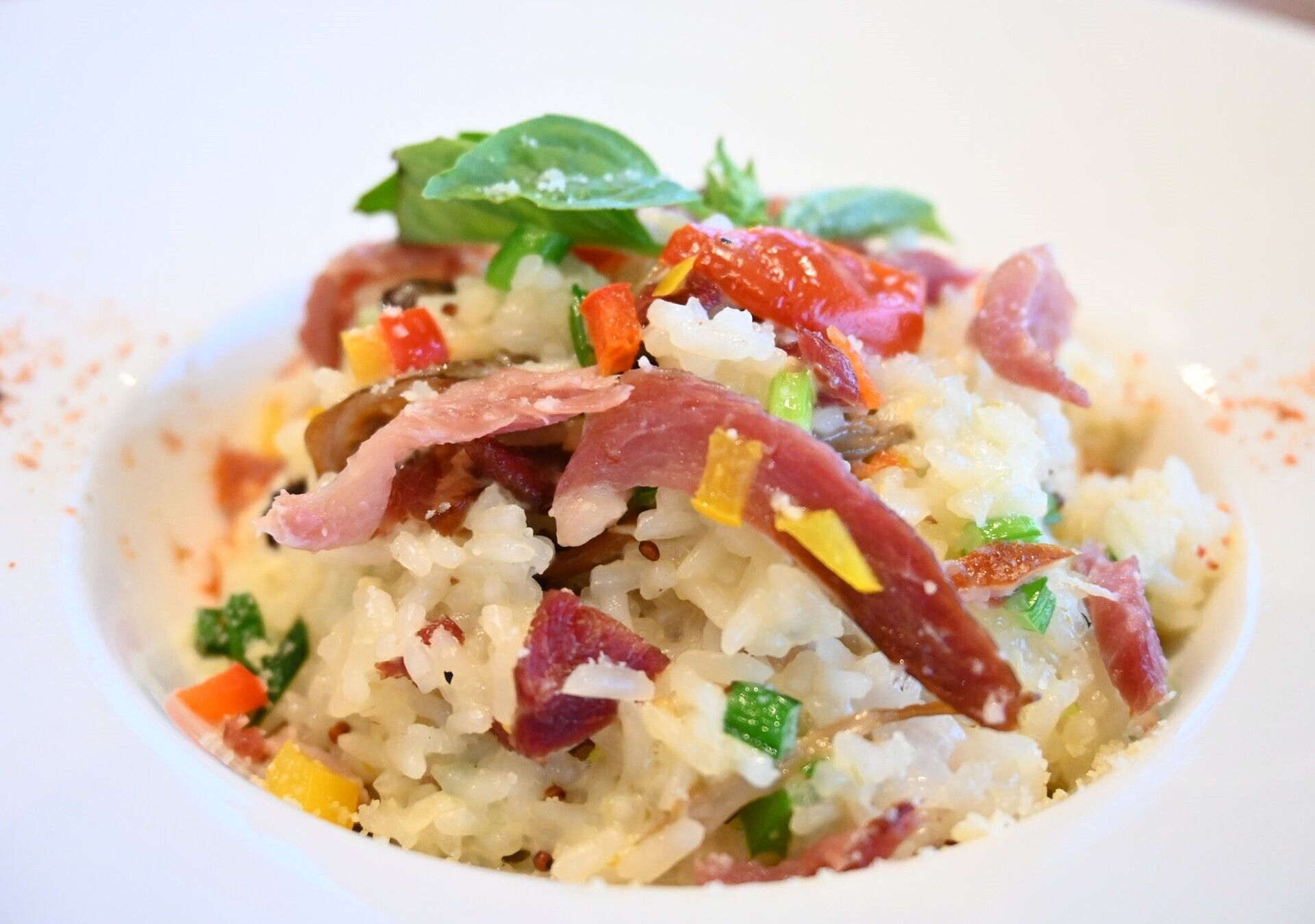 A bowl of rice with vegetables and bacon.