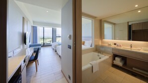 A modern hotel room with a large bed, a desk, a bathtub, and a balcony with a view of the landscape. - Lan Yang Seaview Hotel (Toucheng)