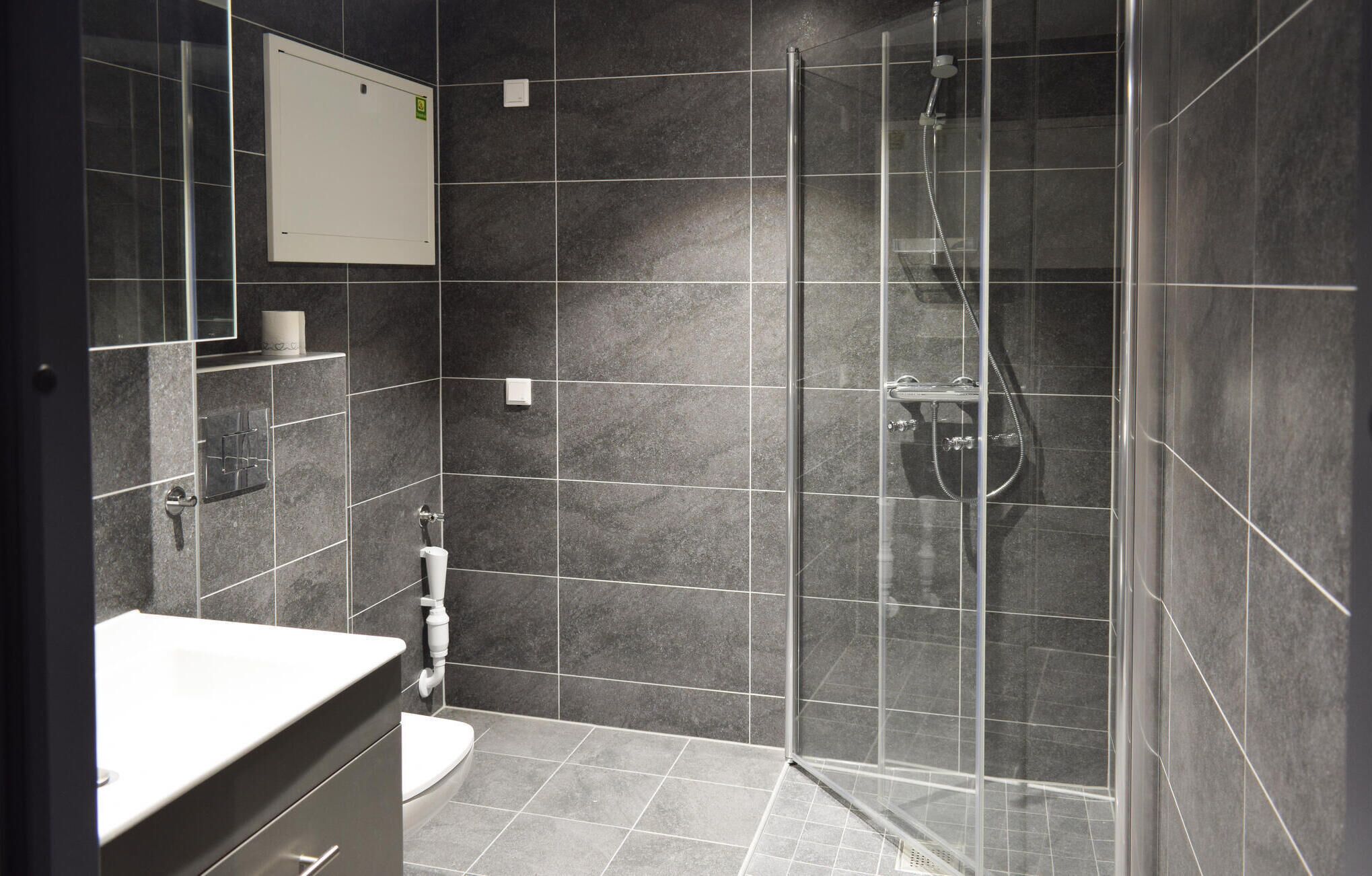 A modern bathroom with a glass-enclosed shower, a toilet, and a sink with a mirror above it.