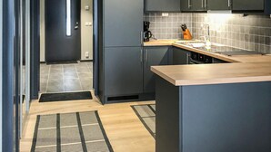 Una cucina moderna con mobili grigi, un piano di lavoro in legno e una parete di fondo rivestita di piastrelle.