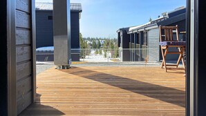 Un pontile in legno con ringhiera metallica, una sedia e un edificio sullo sfondo.
