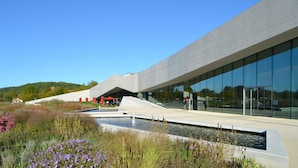 Un bâtiment moderne doté d’un toit en pente et d’une façade en verre réfléchissant.