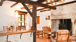 Un intérieur rustique avec des poutres apparentes, une cheminée en pierre et un coin repas agrémenté de meubles en bois.