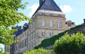 Un bâtiment historique en pierre, doté d’une tour imposante et de nombreuses fenêtres.