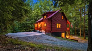 A log cabin with a porch, a driveway, and an American flag. - Log Cabin, UTK/Neyland, Smokies, 16acres, FP, HotTub, GameRoom, Fishing, Pets (Knoxville)