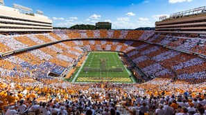 A stadium with tiered seating, a football field, and a large crowd.