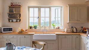 A kitchen with a large window, wooden cabinets, a microwave, and a sink.