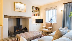 A cozy living room with a fireplace, a bookshelf, a comfortable sofa, and a television.
