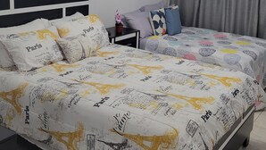 Un dormitorio con cama, mesita de noche, planta en maceta y decoración en la pared.