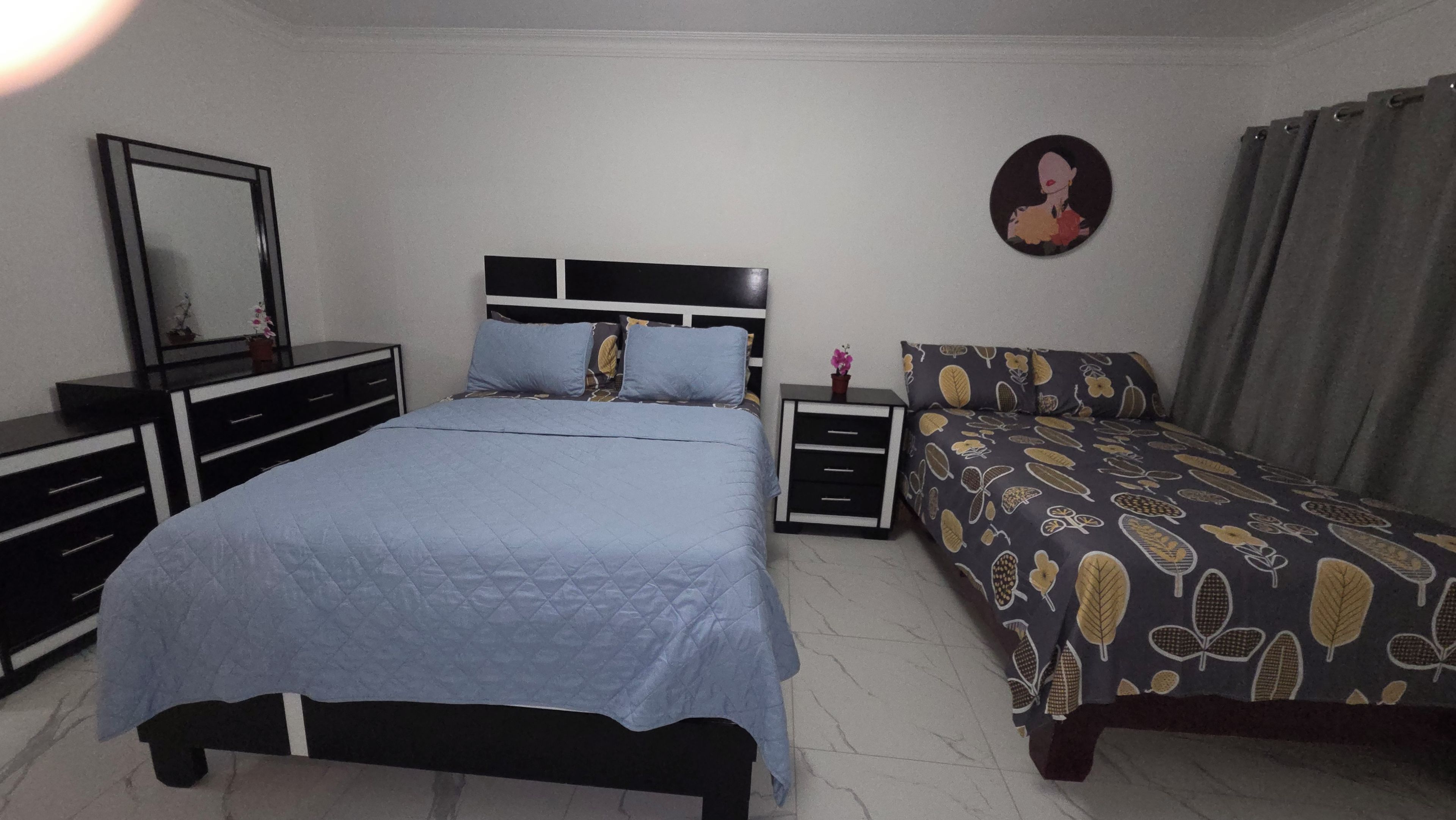 Une chambre à coucher comprenant un lit, une table de chevet, une commode, un miroir et un élément de décoration murale.