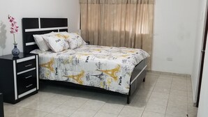 Un dormitorio con cama, mesita de noche, cómoda, ventana con cortinas e iluminación en el techo.