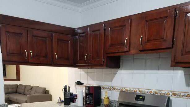 Una cocina con armarios de madera oscura, estufa de acero inoxidable y salpicadero de azulejos.