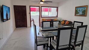 A dining area with a glass-top table, chairs with cushions, a vase with flowers, and a painting on the wall. - Best place to stay, close to everything, you will love it. (Santo Domingo)