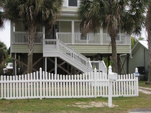 A two-story house with a white picket fence, a front porch, and a staircase leading to the upper level.