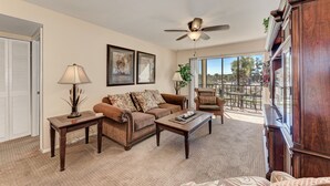 A living room with a brown sofa, a coffee table, a lamp, and framed artwork on the wall. - Siesta Key Beach Condo #1 Beach (Siesta Key)