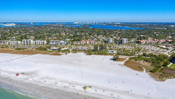 An aerial view of a coastal area with a beach, buildings, and a marina. - Siesta Key Beach Condo #1 Beach (Siesta Key)