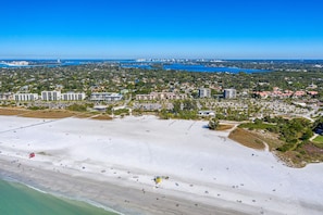 Vista aérea de una zona costera con playa, edificios y un puerto deportivo.