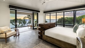A bedroom with a large bed, a wooden dresser, a sofa, and a view of the ocean. - "Iron Man Available" Private Oceanfront Villa W/ detached Ohana and Private Pool (Kailua-Kona)