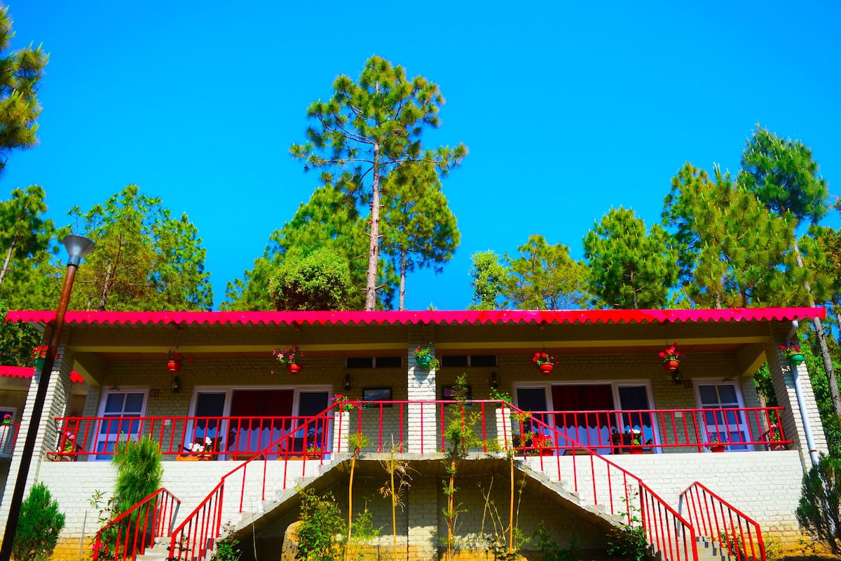 A two-story building with a red roof and balcony railings.