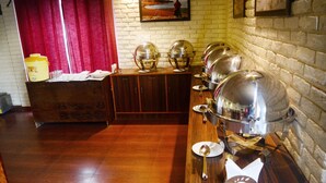 A buffet setup with multiple serving stations, a wooden counter, and a brick wall. - Majkhali Woods, Ranikhet, By Himalayan Eco Lodges (Ranikhet)