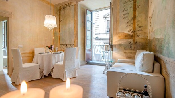A dining area with a table set for four, a chandelier, and a view of the outside.