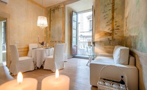 A dining area with a table set for four, a chandelier, and a view of the outside. - Apartment PonteVecchio Signoria (Firenze)