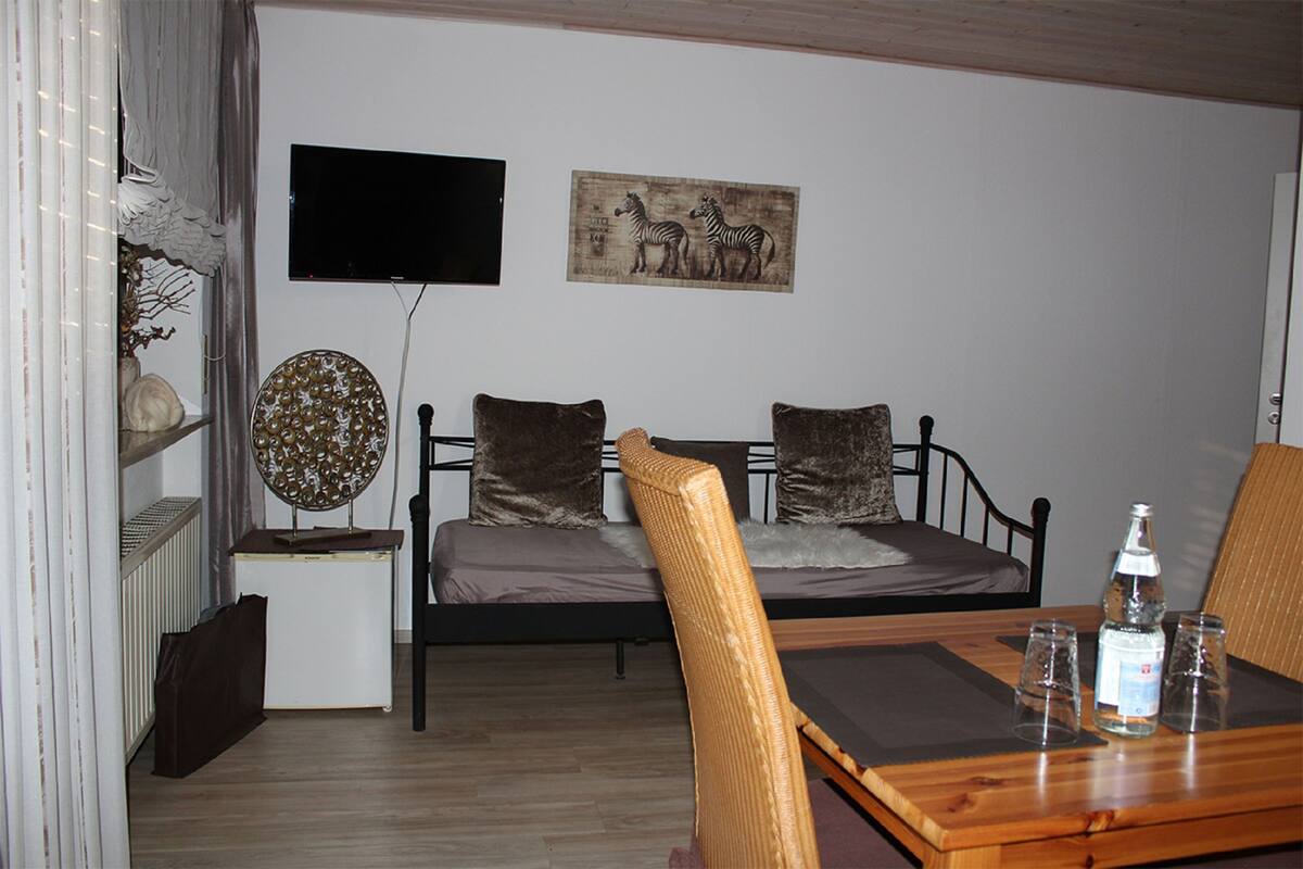 A bedroom with a bed, bedside table, and a TV mounted on the wall.