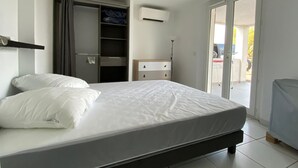 Ein Schlafzimmer mit Bett, Kleiderschrank, Schreibtisch und Balkon.