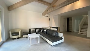 Ein geräumiges Wohnzimmer mit einer Eckcouch, einem weißen Couchtisch und einem Ledersessel.
