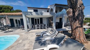 Ein Poolbereich mit Liegestühlen und einer überdachten Lounge.