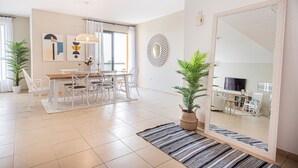 A modern living room with a dining area, large mirror, and potted plants. - Nasma Luxury Stays- Murjan 6, Jumeirah Beach Residence (Dubai)