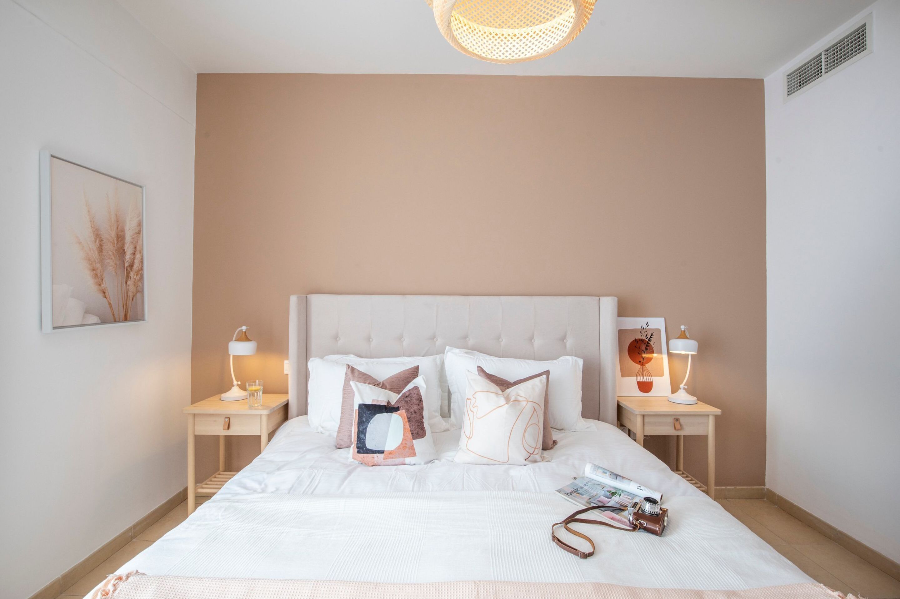 A neatly arranged bedroom with a large bed, two bedside tables with lamps, and a wall-mounted artwork.