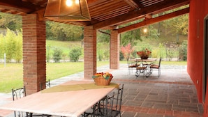 An outdoor patio with a brick table and chairs, surrounded by a brick wall and a wooden ceiling.