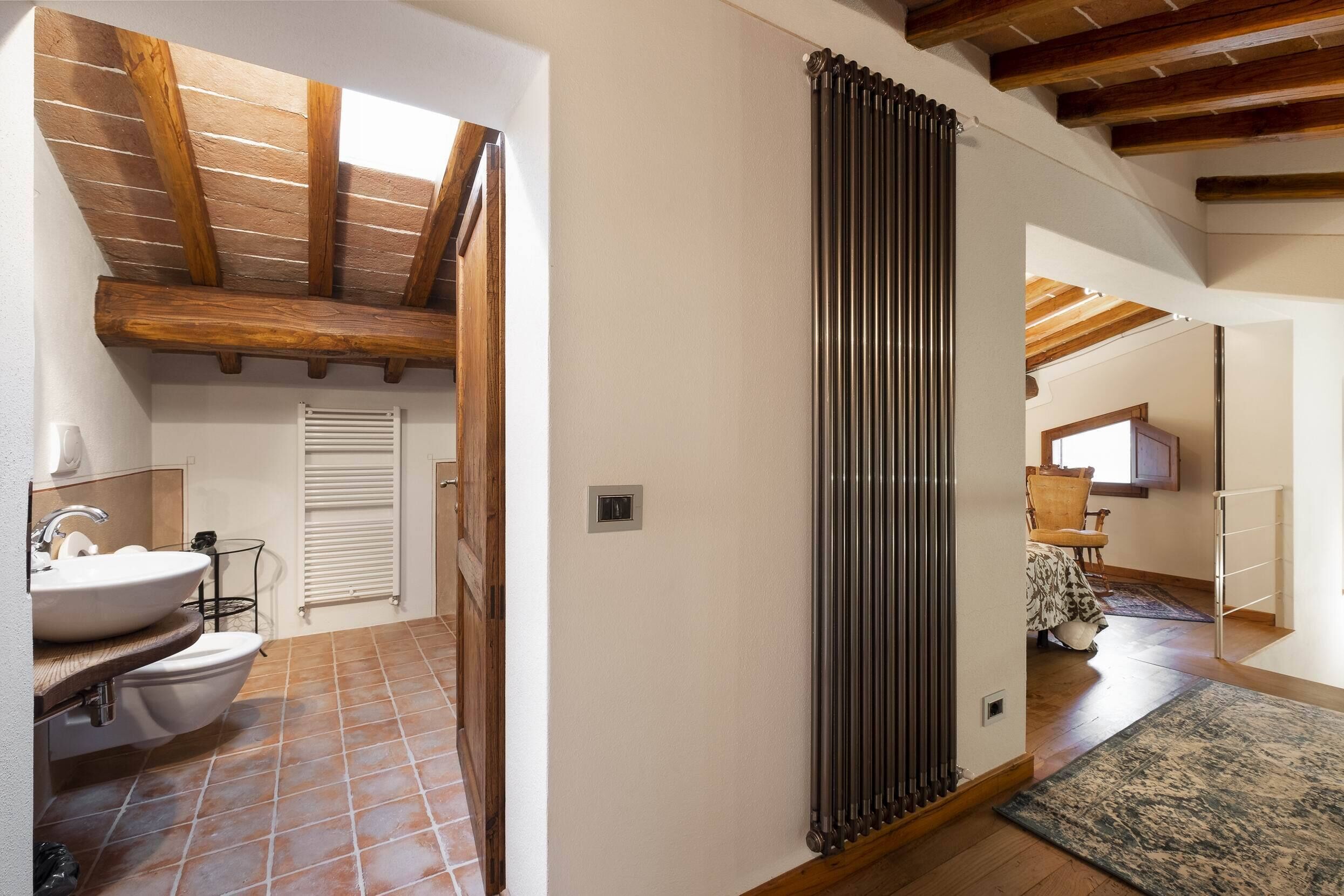 Une salle de bain comprenant un lavabo, des toilettes et un espace douche. Il y a un radiateur au mur et un plafond en bois.