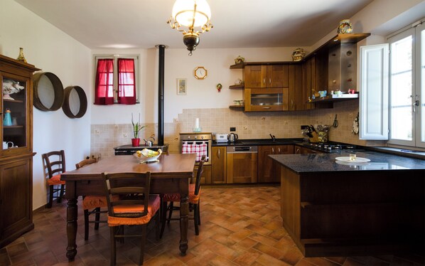 A kitchen with wooden cabinets, a dining table with chairs, a stove, and a sink.