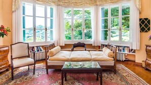A cozy reading nook with a cushioned bench, a glass coffee table, and a bookshelf filled with books. - Stunning 6-bed Private Villa With Pool Near Venice (Vicenza)