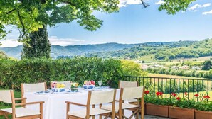 An outdoor dining area with a table set for four, surrounded by wooden chairs. - Stunning 6-bed Private Villa With Pool Near Venice (Vicenza)