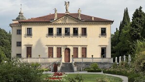 A stately building with a symmetrical facade, a central entrance with steps, and a garden with flowers and shrubs. - Stunning 6-bed Private Villa With Pool Near Venice (Vicenza)