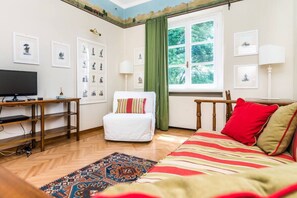 Een kamer met een bed, een bureau, een televisie en een raam met gordijnen.