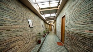 A corridor with stone walls, potted plants, and a skylight.