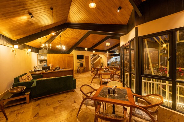 Un hall de hotel espacioso con techos de madera, una recepción, asientos cómodos y grandes ventanales con vistas.
