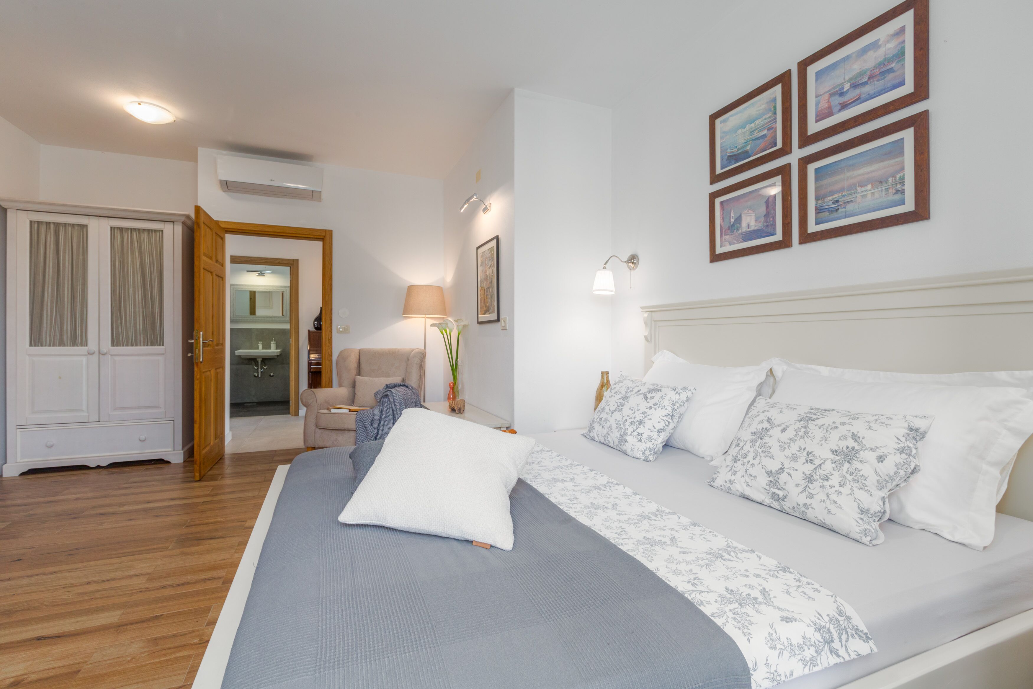 A bedroom with a large bed, a chair, a desk, and a wardrobe.
