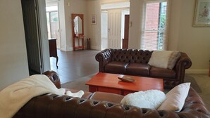 Un salón amplio con un sofá de cuero marrón, una mesa de centro de madera y un plaid blanco y mullido.