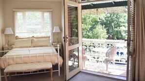 Un dormitorio con cama, mesitas de noche, lámparas y un balcón con una silla.