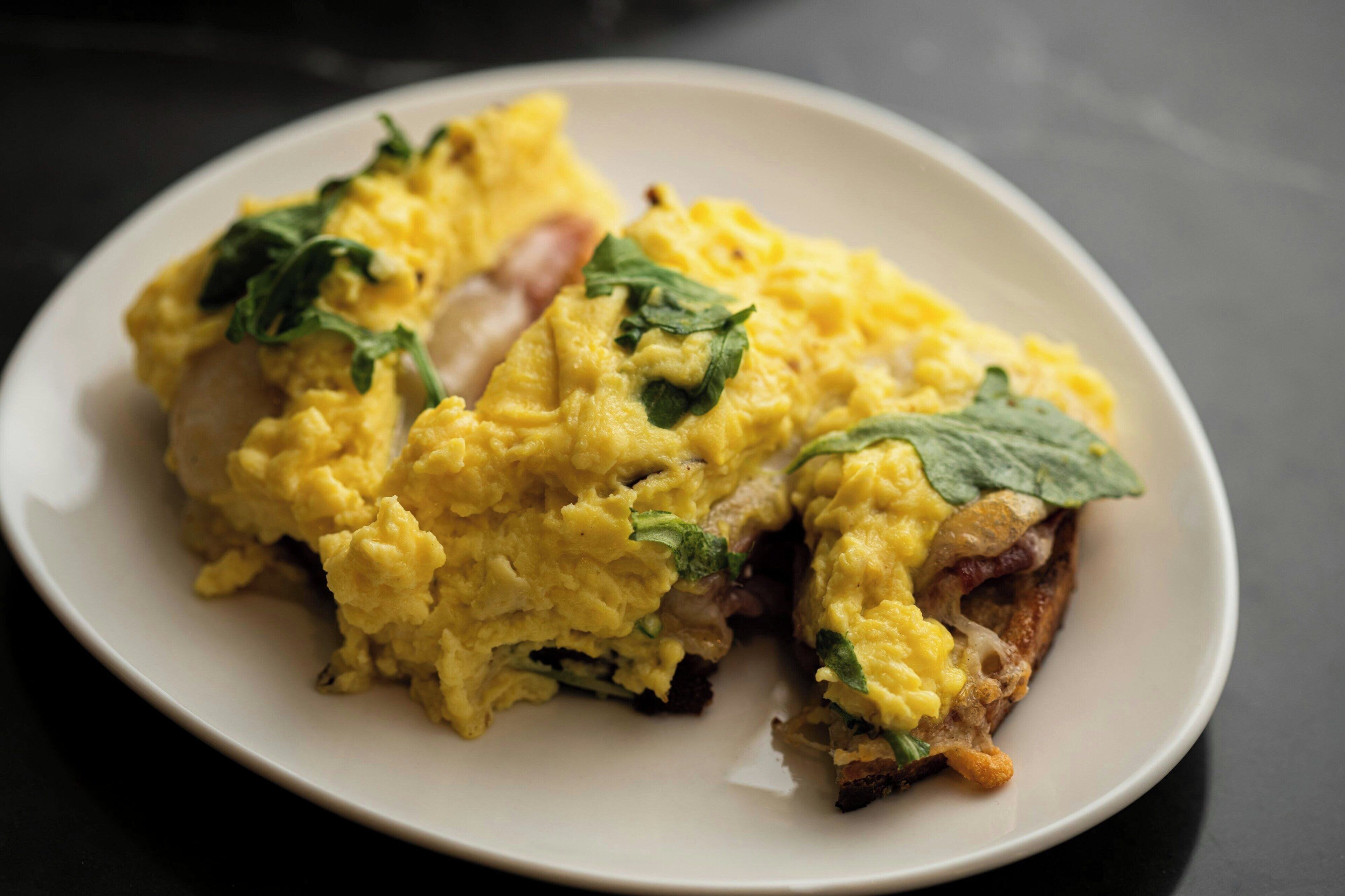 A plate of scrambled eggs with spinach on a white plate.