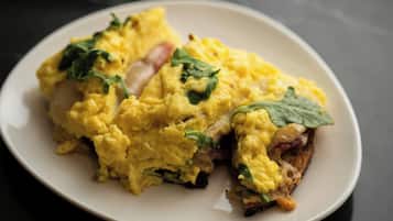 A plate of scrambled eggs with spinach on a white plate.