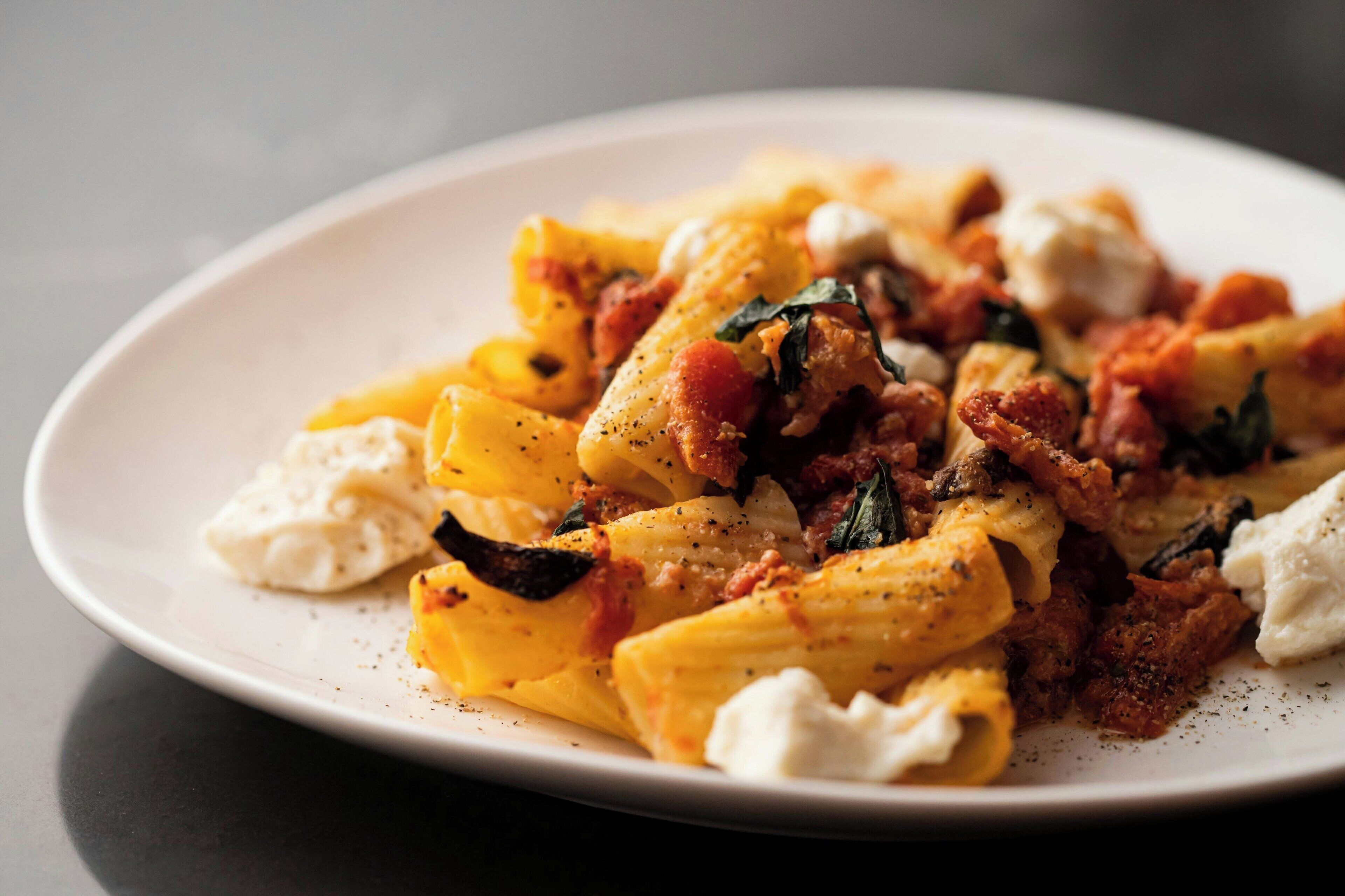 A plate of pasta with tomato sauce, cheese, and herbs.