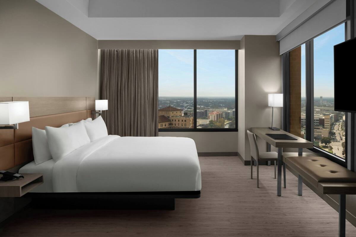 Une chambre d’hôtel avec un grand lit, un bureau et une vue sur la ville.