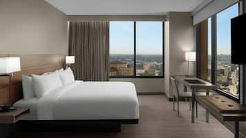 A hotel room with a large bed, a desk, and a view of the city.