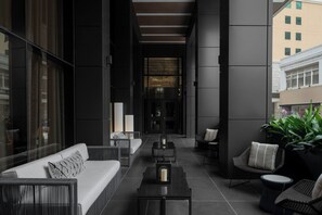 A modern outdoor lounge area with a sofa, chairs, and tables. - AC Hotel by Marriott San Antonio Riverwalk (San Antonio)
